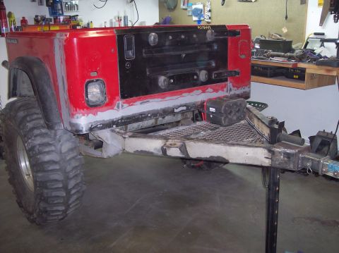 2003 Jeep TJ - The rear of a Jeep TJ is shown with a custom trailer hitch. The vehicle appears to be undergoing modifications or repairs.