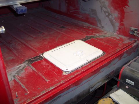2003 Jeep TJ - The interior cargo area of a vehicle shows exposed metal and a white access panel.