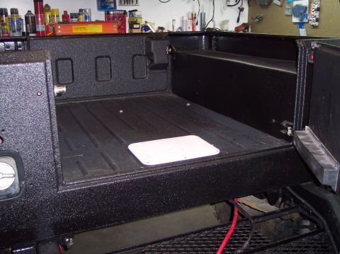 2003 Jeep TJ - The textured bed liner of a vehicle is visible, with a white access panel on the floor.