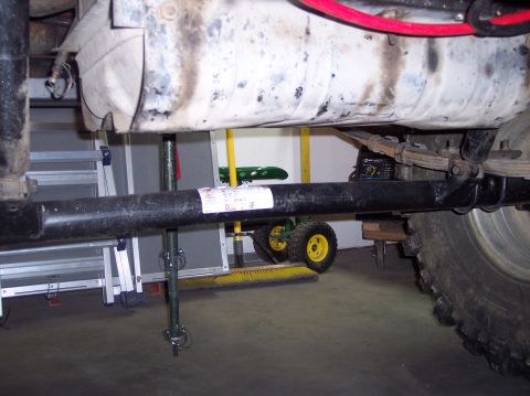 2003 Jeep TJ - Close-up view of the undercarriage, focusing on mechanical parts and a white label attached to the exhaust pipe.
