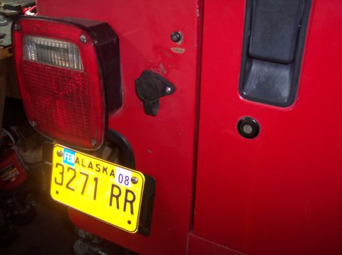 2003 Jeep TJ - Rear view of a red Jeep TJ, showing the taillight and an Alaska license plate.