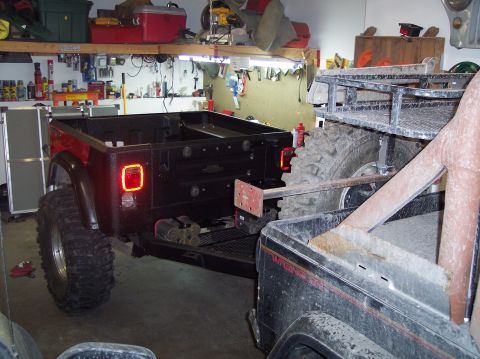 2003 Jeep TJ - Modified Jeep pickup truck bed with aftermarket taillights and large off-road tires.