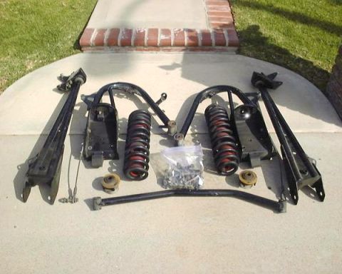1984 Ford Bronco - Various black suspension parts, including control arms and springs, are arranged on a concrete surface.