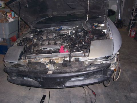 1996 Ford Probe - The front bumper and hood are removed, exposing the engine bay of a car.