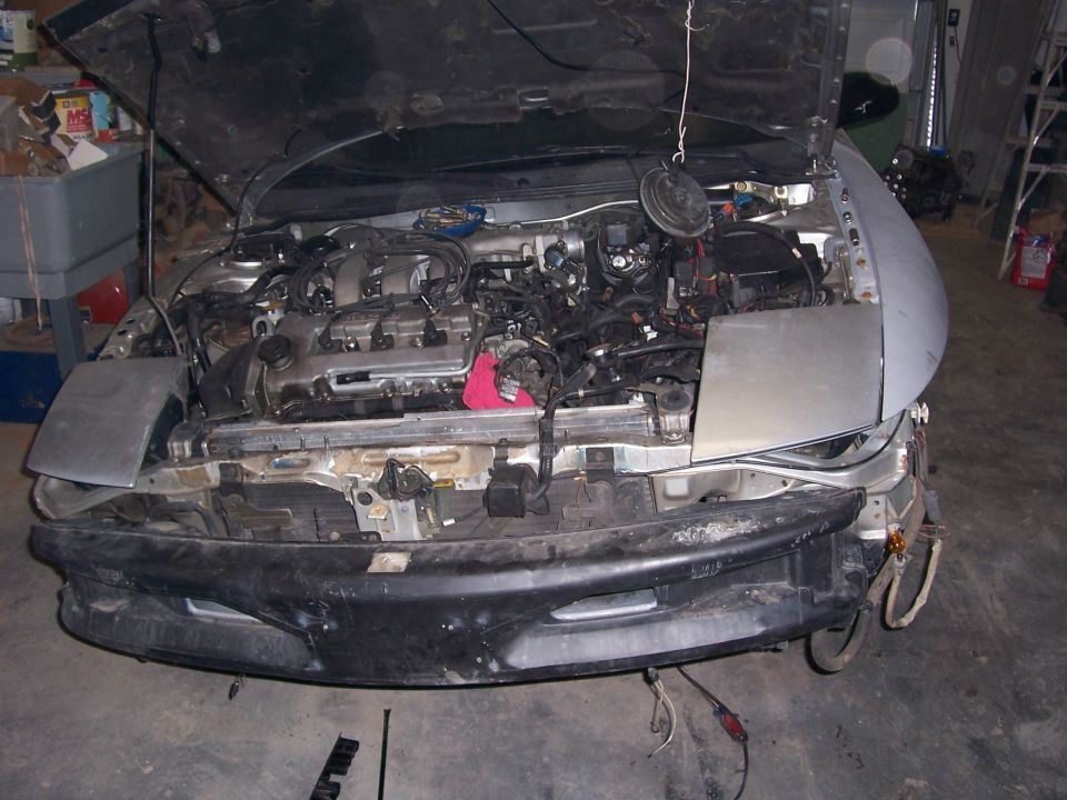 car with hood up, showing engine and front bumper removed
