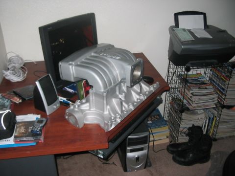 1991 Ford Bronco - A silver engine intake manifold sits on a desk, obscuring a computer monitor and speakers.