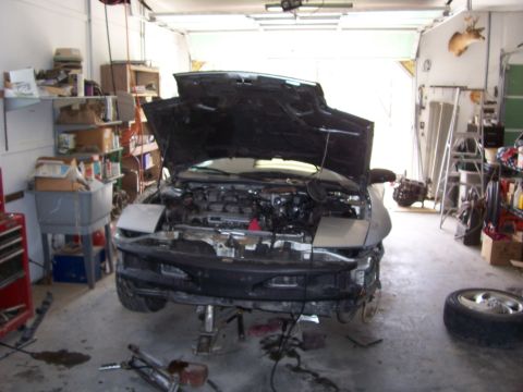 1996 Ford Probe - A car is being worked on in a garage, with its hood open and engine visible.