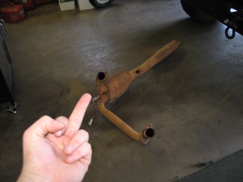 1995 Ford Bronco - A rusty exhaust part is shown on the floor of a garage.