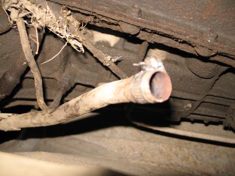 1995 Ford Bronco - Close-up view of a rusty exhaust pipe attached to the undercarriage of a vehicle.