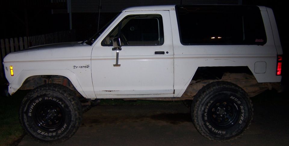White 1984 Ford Bronco II parked outside at night, lifted with off-road tires