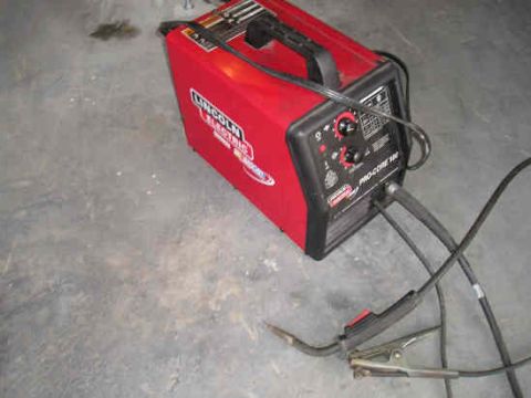 2002 Ford F-150 - A red Lincoln Electric welder sits on a concrete floor, connected to cables and a welding torch.