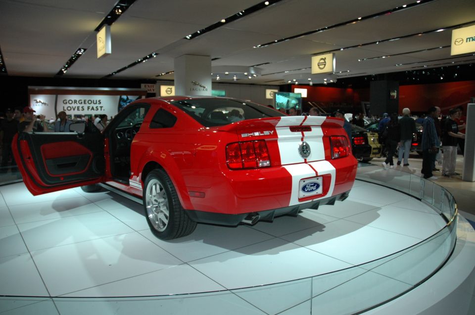 Red 2005 Ford Mustang Shelby with white stripes, driver's door open, on display
