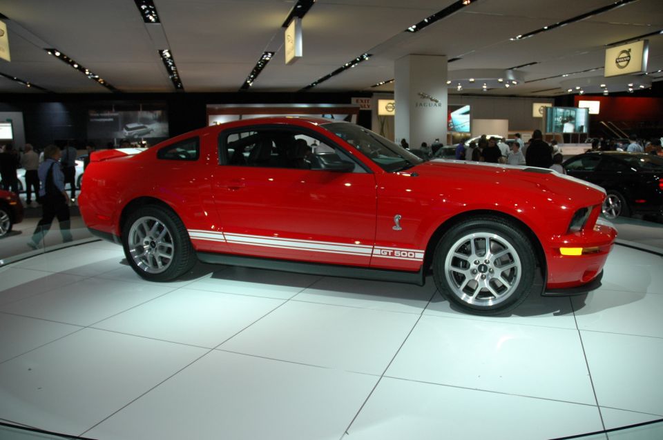 Red 2005 Ford Mustang GT500 with white racing stripes on display