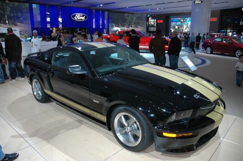 2005 Ford Mustang - A black 2006 Ford Mustang Shelby GT-H is displayed with gold stripes and other vehicles in the background.
