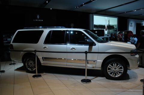 2005 Ford Mustang - A white Lincoln Navigator L is displayed indoors, its side profile and chrome detailing.