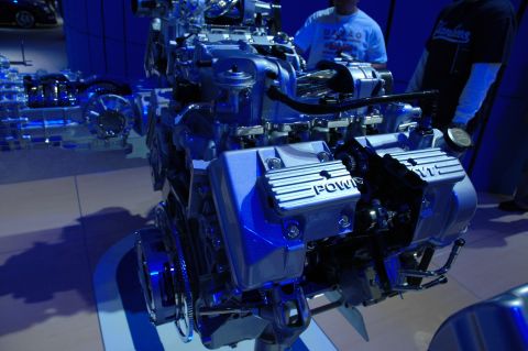 2005 Ford Mustang - A V8 engine is displayed under blue lighting, with people in the background.