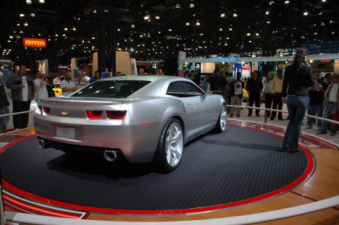 2005 Ford Mustang - A silver Chevrolet Camaro concept car is displayed on a rotating platform at an auto show.