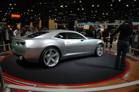 2005 Ford Mustang - A silver coupe, likely a Chevrolet Camaro concept, is presented on a rotating display at an auto show.