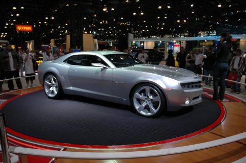 2005 Ford Mustang - Silver concept car displayed at an auto show with spectators in the background.