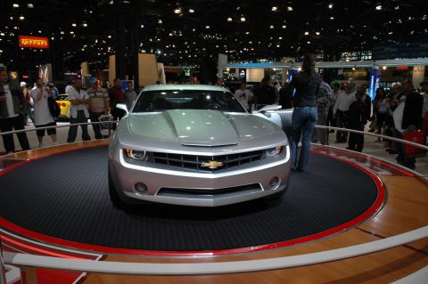2005 Ford Mustang - A silver Chevrolet Camaro concept car is displayed on a rotating platform at an auto show.