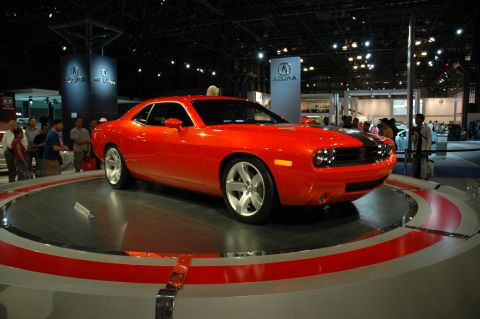 2005 Ford Mustang - A bright red Dodge Challenger concept car is displayed on a rotating platform at an auto show.