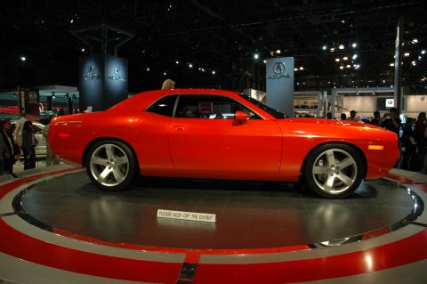 2005 Ford Mustang - A red coupe is displayed on a turntable at an auto show, with a sign indicating not to step on the exhibit.