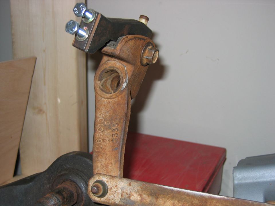 Rusty cast steering pitman arm held in a vise with bolts and cast numbers