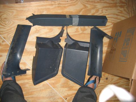1992 Ford Bronco - Several dark grey plastic interior trim pieces are arranged on a wooden surface, possibly for sale or storage.
