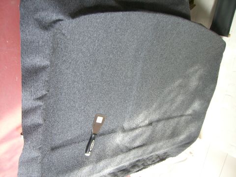 1988 Ford Bronco - A putty knife is placed on the dark carpeted floor of a vehicle.