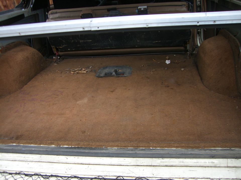 Brown carpeted cargo area of an SUV with rear seat folded and tan side panels