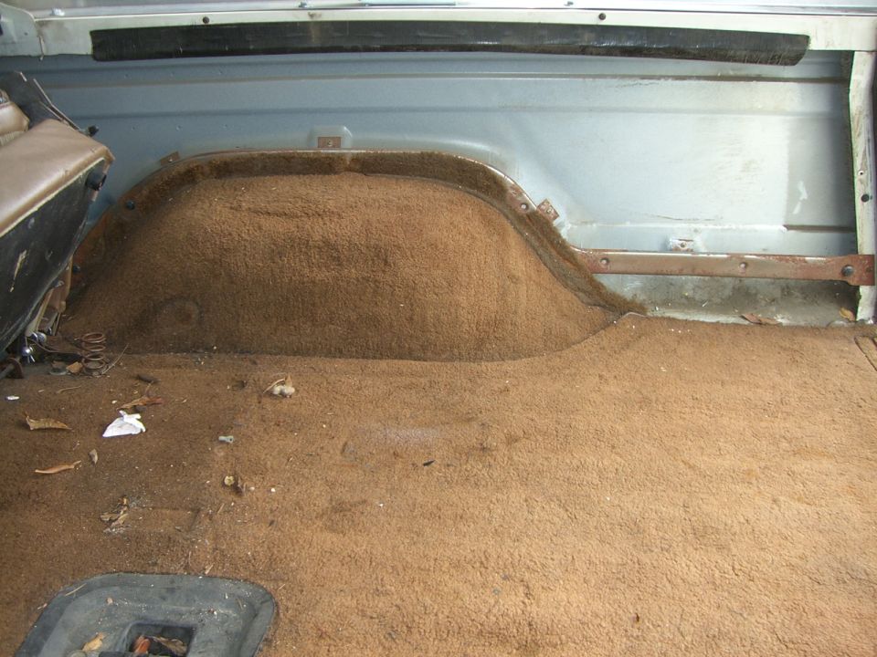 Brown carpeted rear cargo floor over wheel hump in a light blue SUV interior