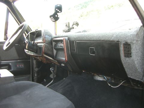 1988 Ford Bronco - Interior view of a 1988 Ford Bronco, a fuzzy grey carpeted dashboard and dice hanging from the rearview mirror.
