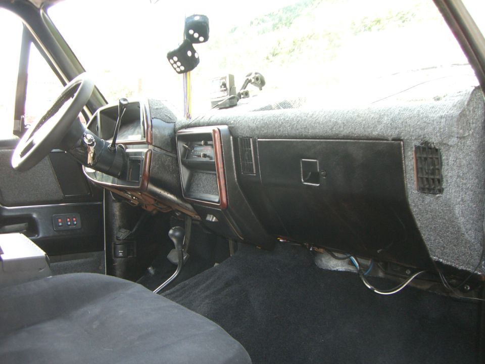 1988 Ford Bronco interior showing dashboard, steering wheel, and fuzzy grey carpet on dash
