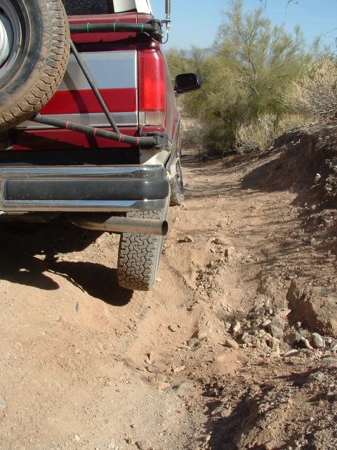 1990 Ford Bronco - Pickup truck navigates a challenging off-road trail in a desert environment.