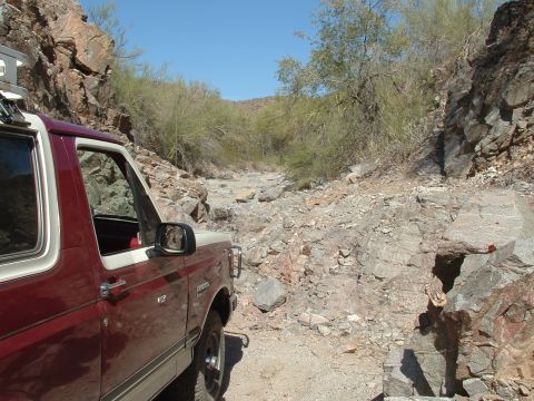1990 Ford Bronco - A Ford Bronco navigates a rough, rocky path through a desert canyon.