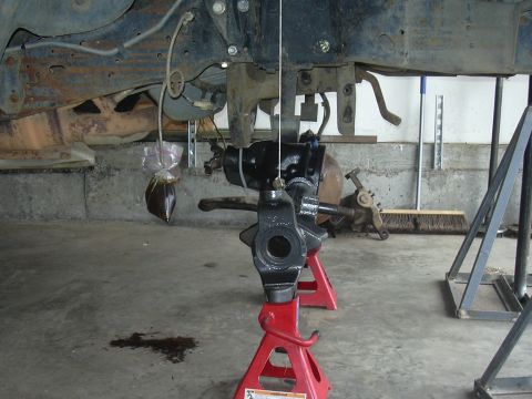 1991 Ford Bronco - Close-up of a vehicle's suspension component being worked on, supported by jack stands.
