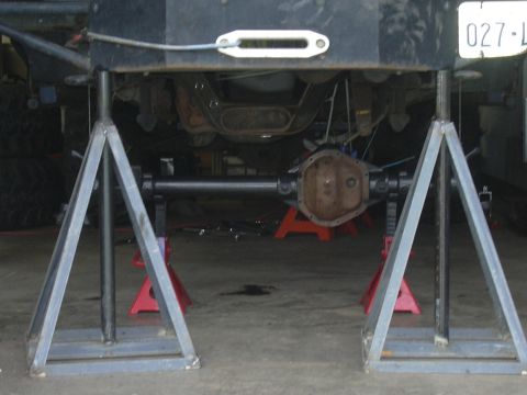 1991 Ford Bronco - The underside of a vehicle, specifically the rear axle assembly, is supported by jack stands for maintenance.