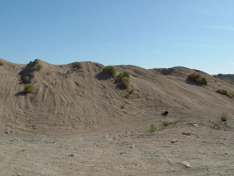 1990 Ford Bronco - Off-road tire tracks mark the sandy hills, indicating recent vehicle activity in the area.