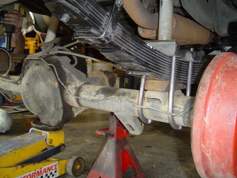 1989 Ford Bronco - Close-up of a vehicle's rear axle and leaf spring suspension system during maintenance.