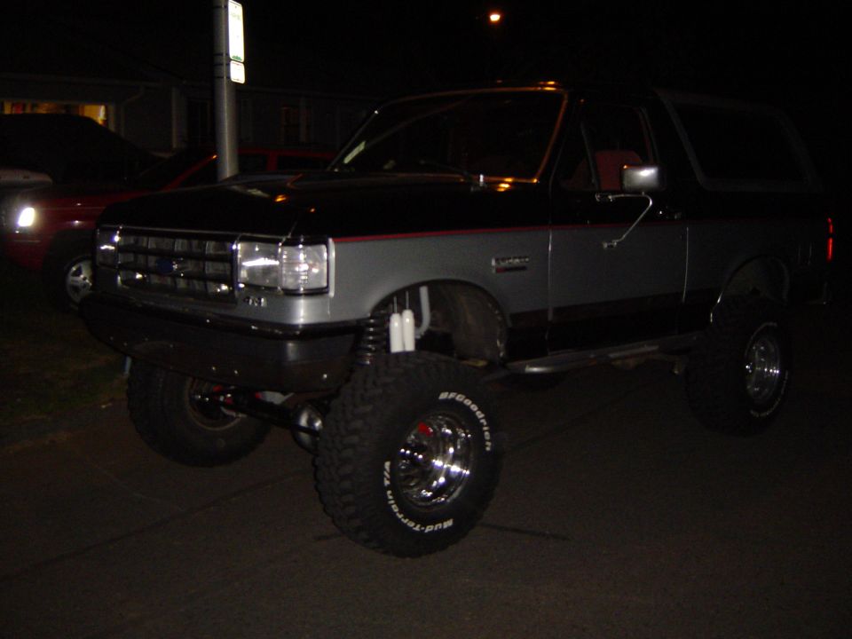 Lifted black and silver Ford Bronco on BFG Mud-Terrains at night, front three-quarter view