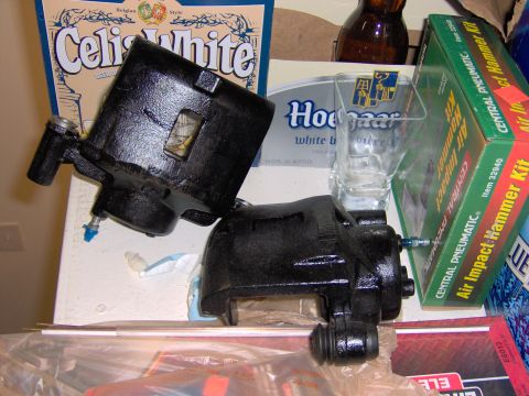 1993 Ford Probe - Two brake calipers are displayed with various items in the background, including beer packaging and tool kits.