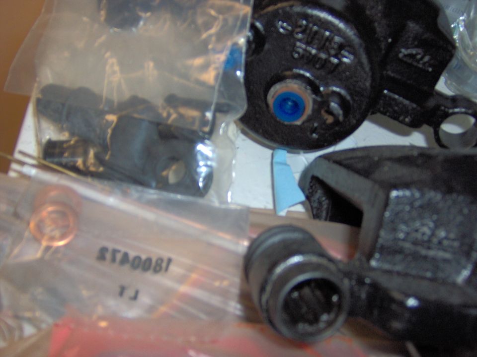 Brake caliper parts in plastic bags and loose. Text "STA0081 YJ" visible on one bag