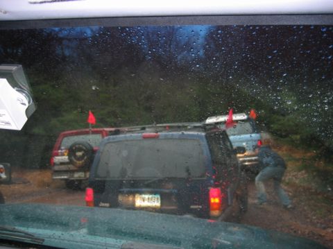 1995 Ford Bronco - Multiple SUVs navigate a muddy off-road trail, some equipped with flags.