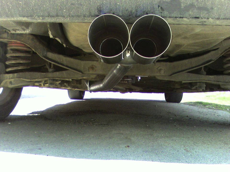 Underside of a car showing a dual exhaust system with chrome tips