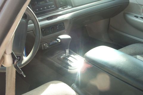 1999 Ford Crown Victoria - Interior of a late-1990s Ford Crown Victoria viewed through the driver's door, showing a gray dash, a floor console with automatic shifter,…
