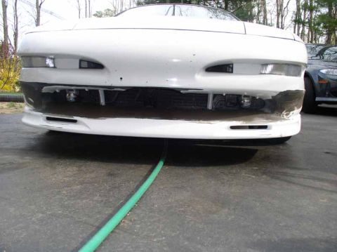 1996 Ford Probe - Front view of a white 1996 Ford Probe GT with a damaged bumper and a hose running under it.