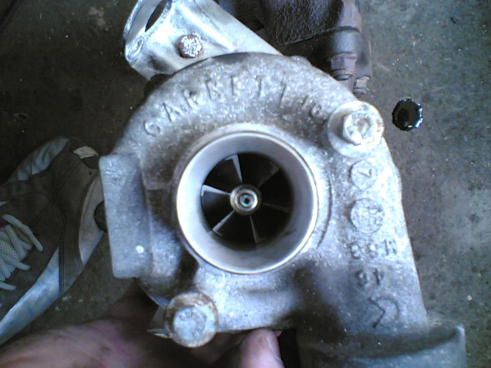 Garrett turbocharger compressor housing and wheel held over a concrete floor