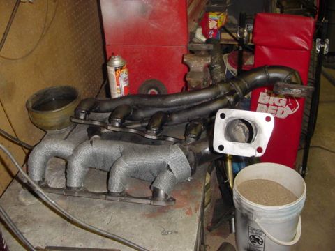 1995 Ford Mustang - Custom exhaust manifold and turbo piping assembly, partially wrapped in heat-resistant material.