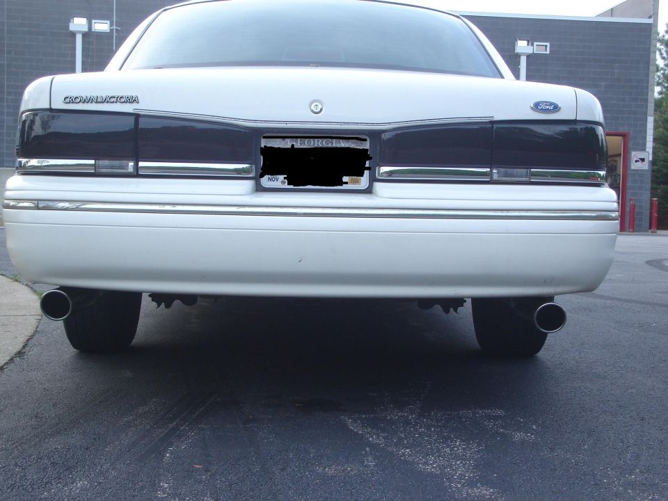 Rear view of a white 1995 Ford Crown Victoria with tinted taillights and dual exhaust pipes
