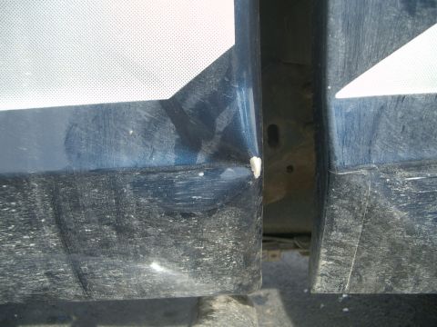 1992 Ford Ranger - Close-up view of the door seam on a blue truck, showing a dent and a partial white graphic on the panel.